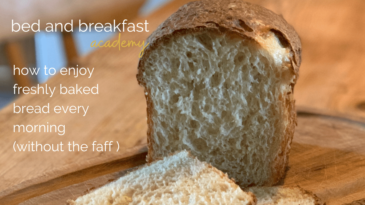 A loaf of crusty white bread with the end sliced off on a wooden boards