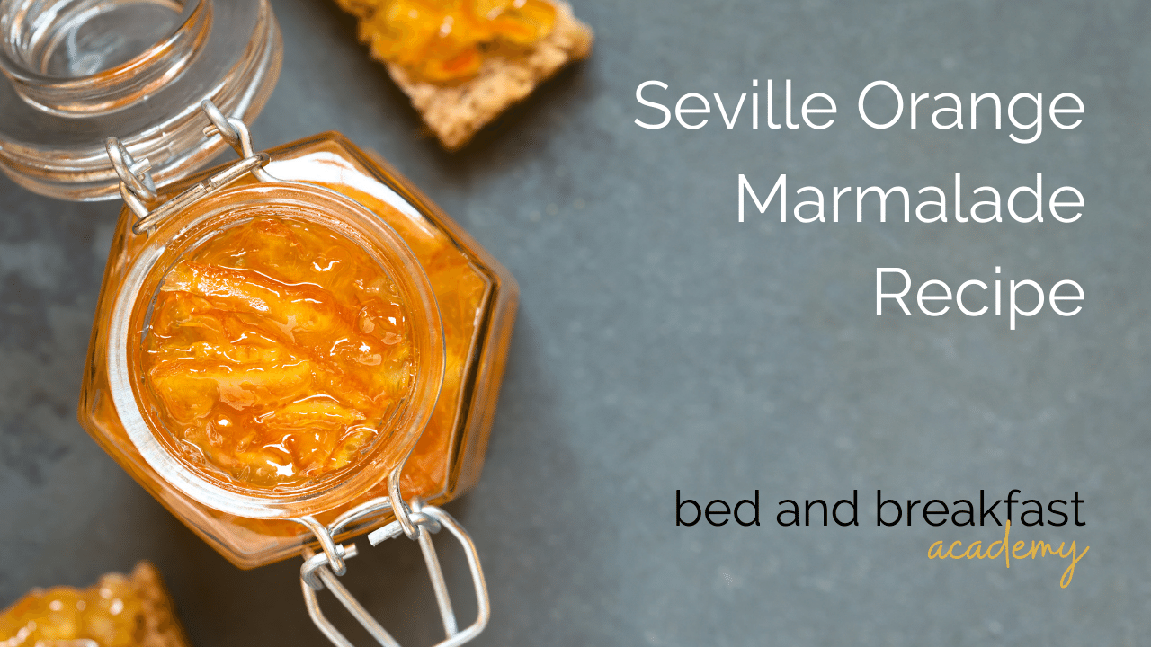Top down view of an open jar of seville orange marmalade on a grey surface with some marmalade toast soldiers