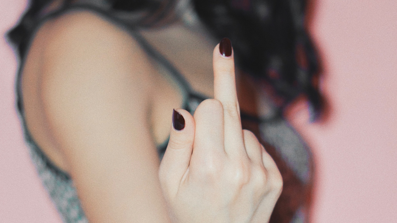 Woman with middle finger up - fuck you - blog is about getting back up again after multiple set backs ans standing in truth of soul's purpose