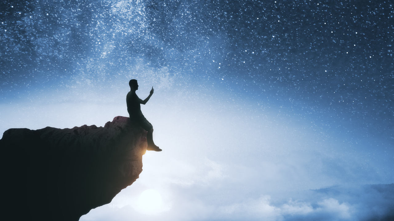 Person sat comtemplating life and the world with the whole world and cosmos before him as he thinks of his vision and purpose