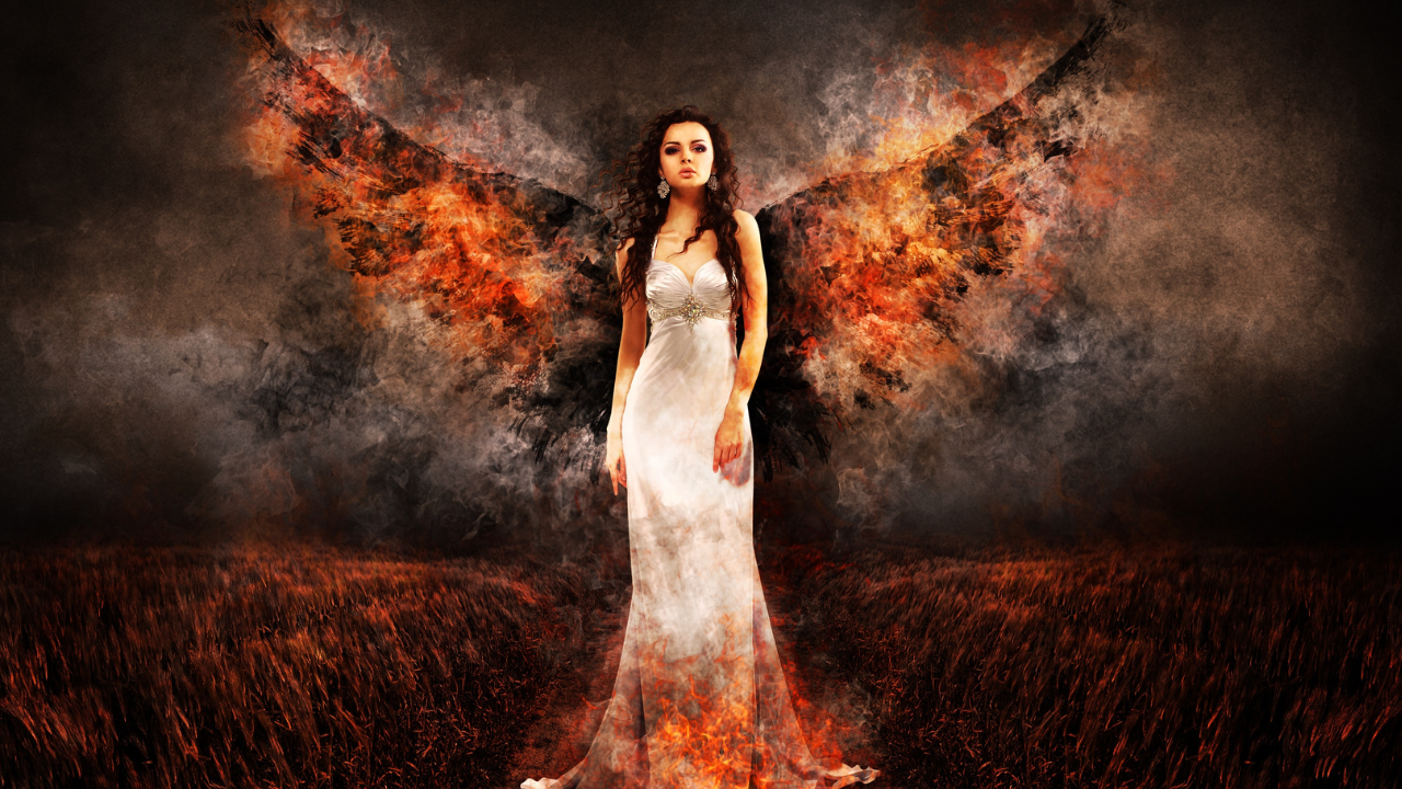 Angel woman stands in the fire with fire on her wings as she looks fierce - representing the phoenix rising and a woman in her power and truth as she rises from the ashes