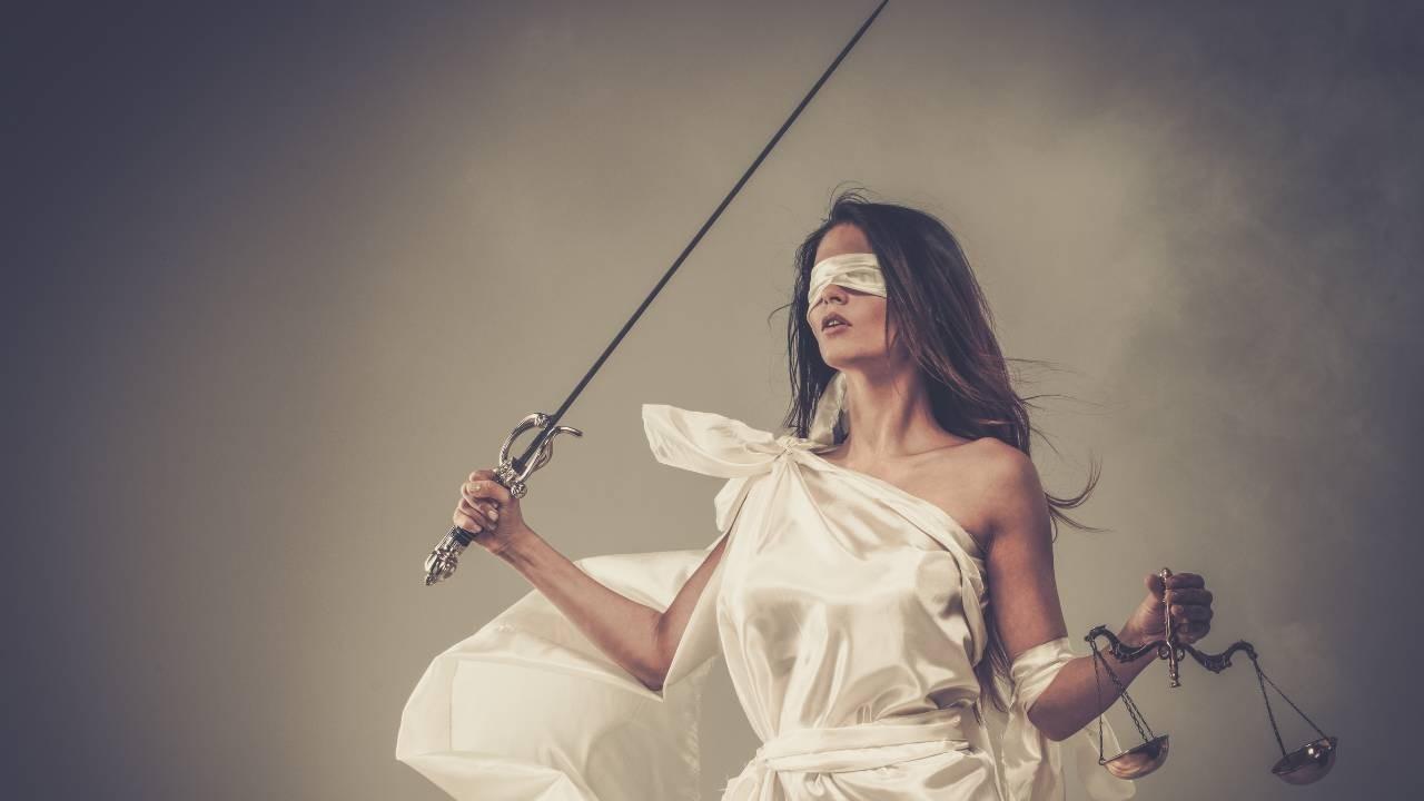 Blindfolded Lady Justice holds the scales and swords to represent truth