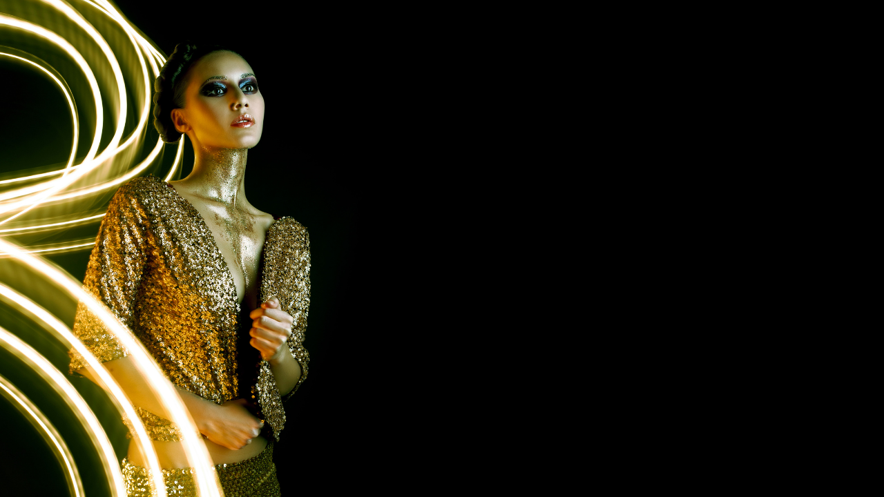 woman dressed in gold known as a cosmic girl with a black background with the contracting black and gold to represent the gold within the shadow