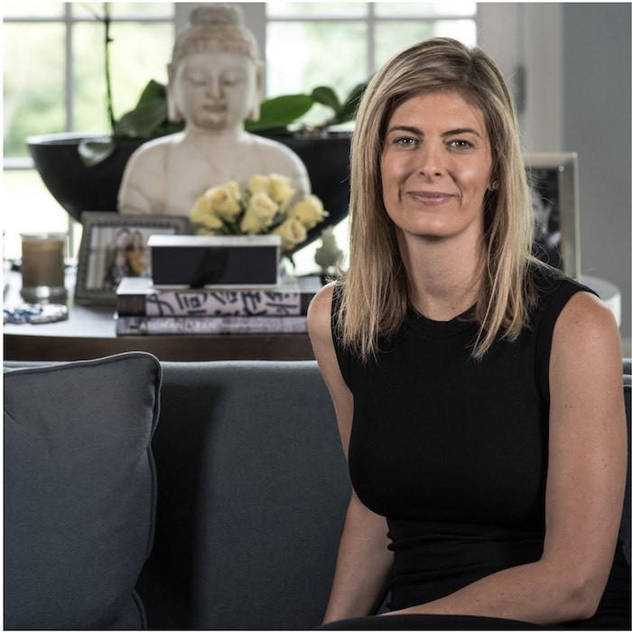 Megan Cooper wearing black top sitting on lounge at home