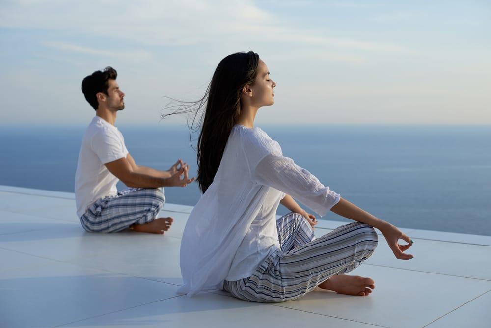 Man and woman seated meditating outside