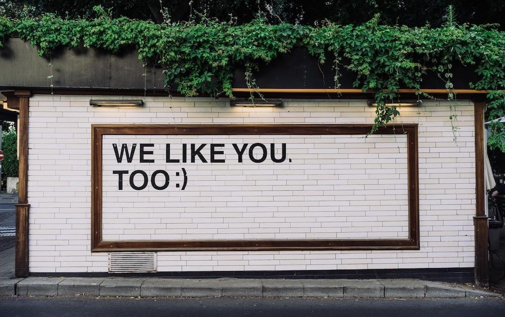 Brick wall painted with the words: We Like You, Too :)