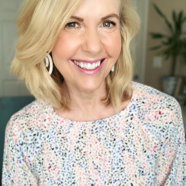 Woman with blonde hair and colorful shirt smiling.