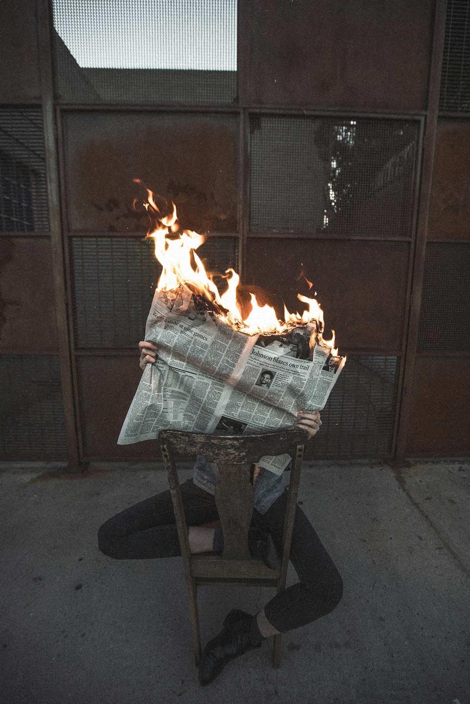 Person reading a newspaper that's on fire