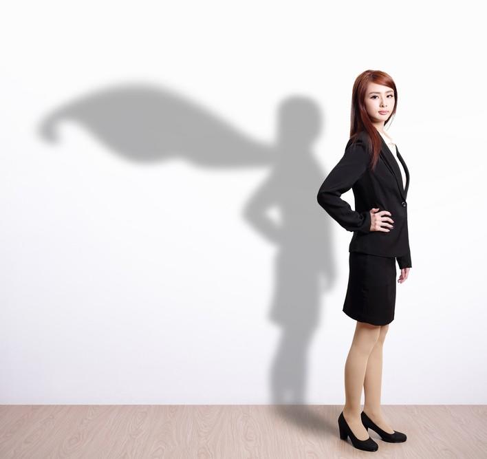 Asian woman in business suit with a shadow in the shape of super woman