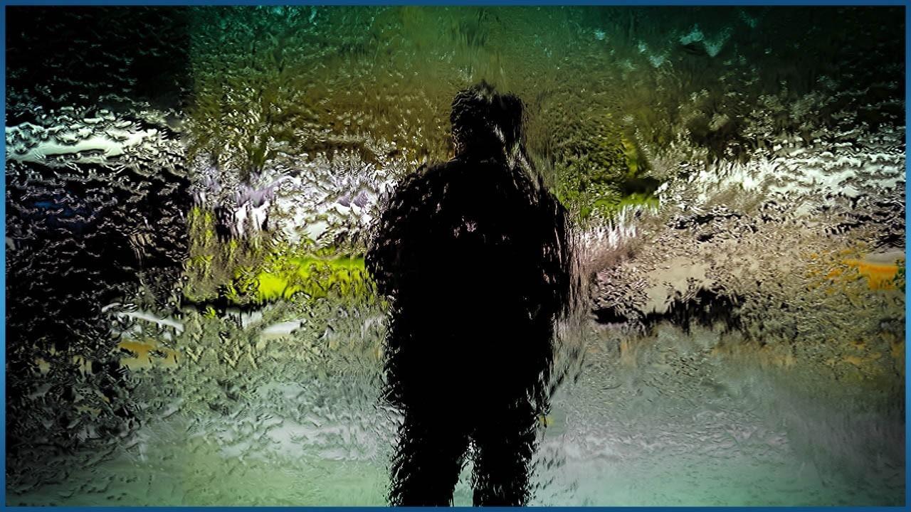 person standing behind mosaic glass