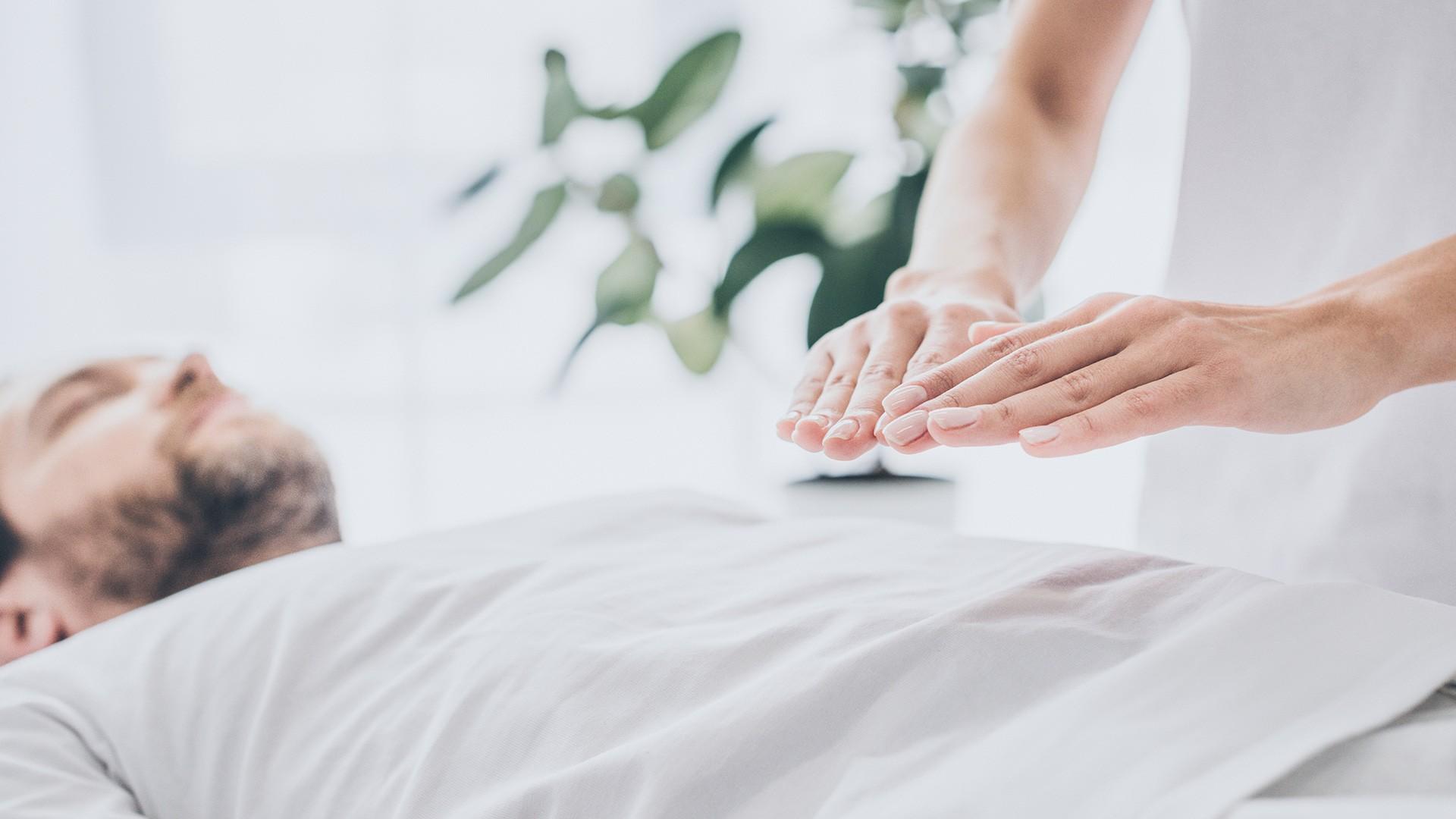 woman holding hands above a man's abdomen - Therapeutic Touch Services are available at pureBalance Wellness in Mississauga