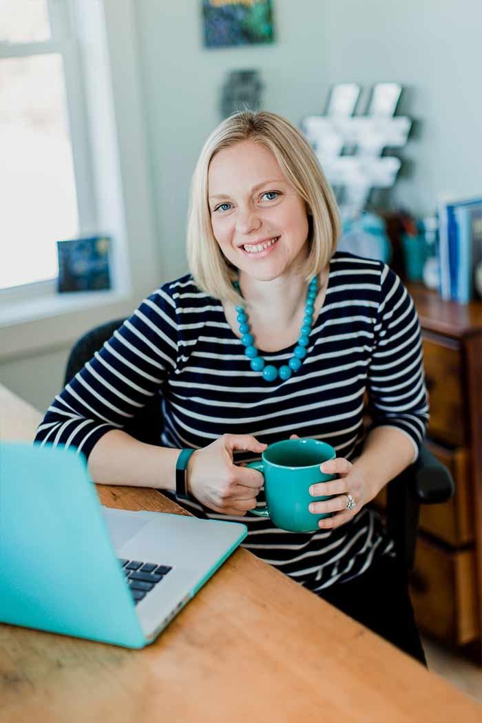 Picture of Stacey Nachajski sitting at desk with laptop and teal mug
