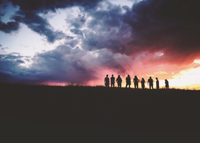 friends standing on hill at sunset