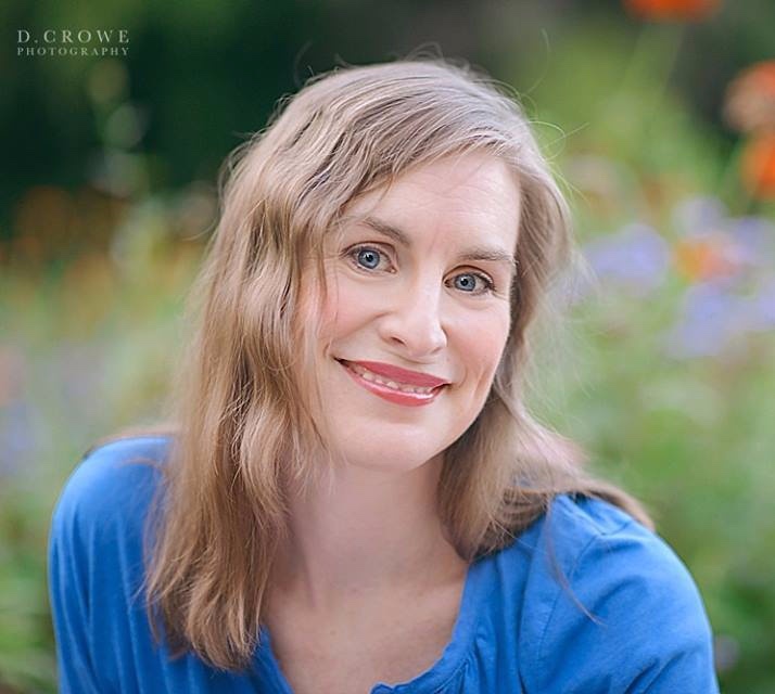 woman in blue shirt sitting in field of flowers