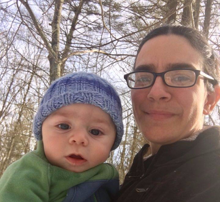 woman with glasses holding baby outside