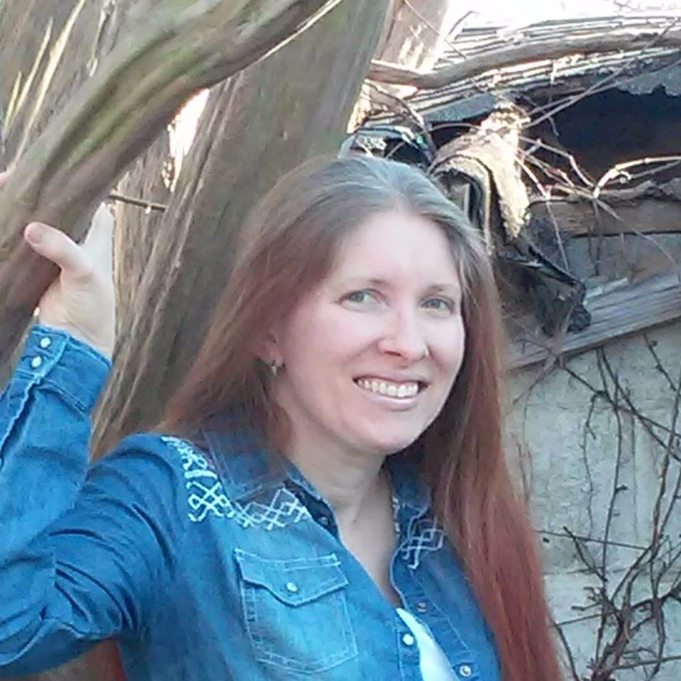 woman in jean jacket standing next to trees