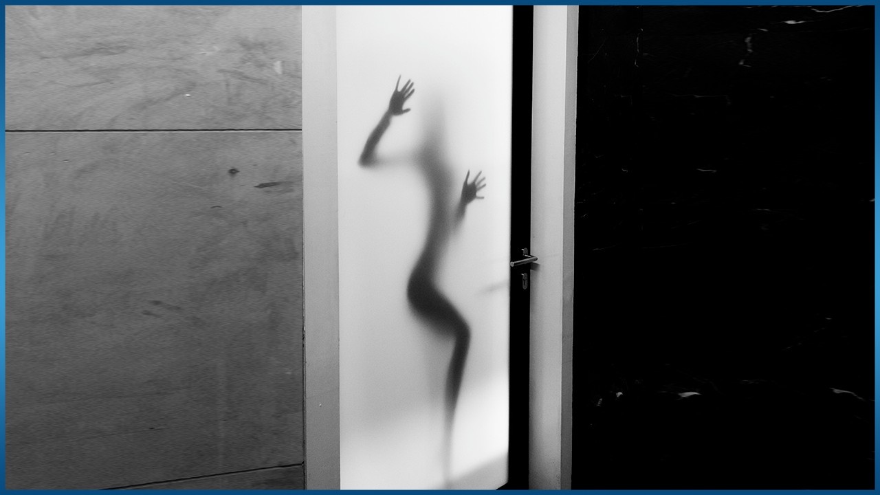 naked female figure standing behind glass