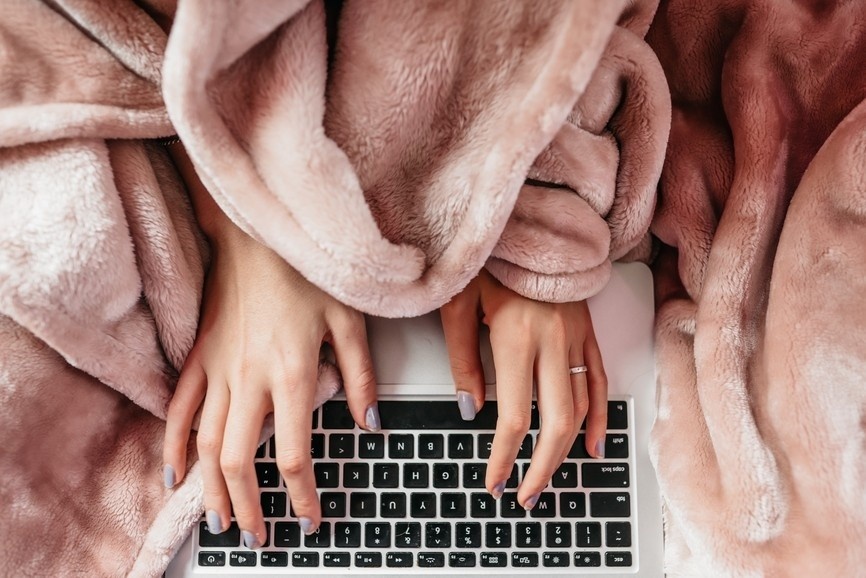 female entrepreneur takes a break mid-day and reclines on the couch, feet in air, experiencing joy