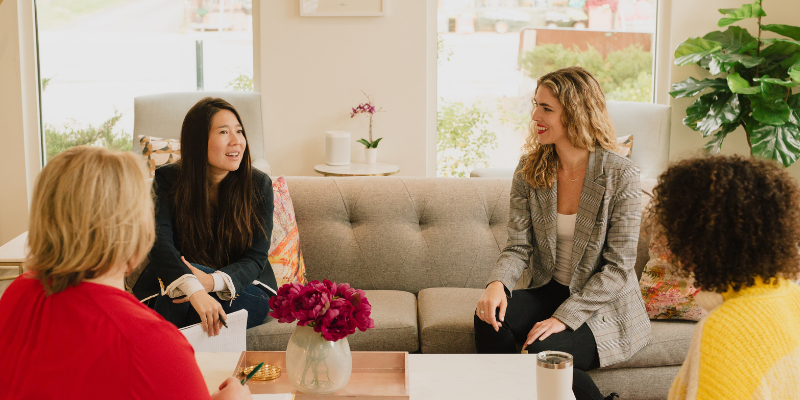 Small group of four women sitting on couches discussing social media